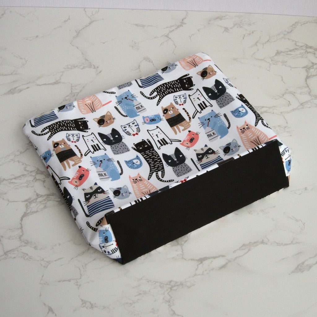 Large and generously sized cat print design wash bag with a 100% cotton outer, lying flat, at an angle, fastening with a quality white nylon zip, and a gusseted boxed bottom, placed on a marble surface.