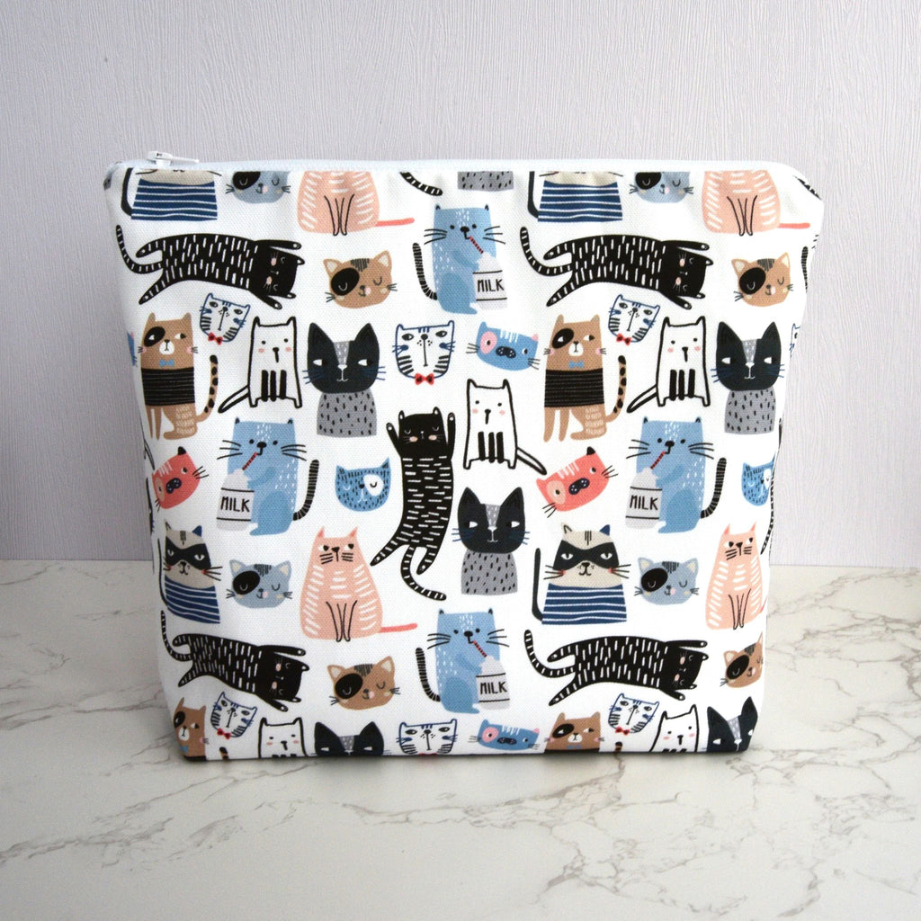 Large and generously sized cat print design wash bag with a 100% cotton outer, closed, fastening with a quality white nylon zip, and a gusseted boxed bottom, so that it sits upright, placed on a marble surface, with a white background.
