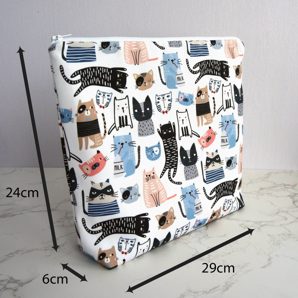 Large and generously sized cat print design wash bag with a 100% cotton outer, closed, fastening with a quality white nylon zip, and a gusseted boxed bottom, so that it sits upright, placed on a marble surface, with a white background, annotated with arrows and measurements, of 29cm width, 24cm height and 6cm depth.
