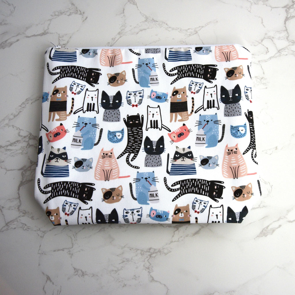 Large and generously sized cat print design wash bag with a 100% cotton outer, lying flat, fastening with a quality white nylon zip placed on a marble surface.