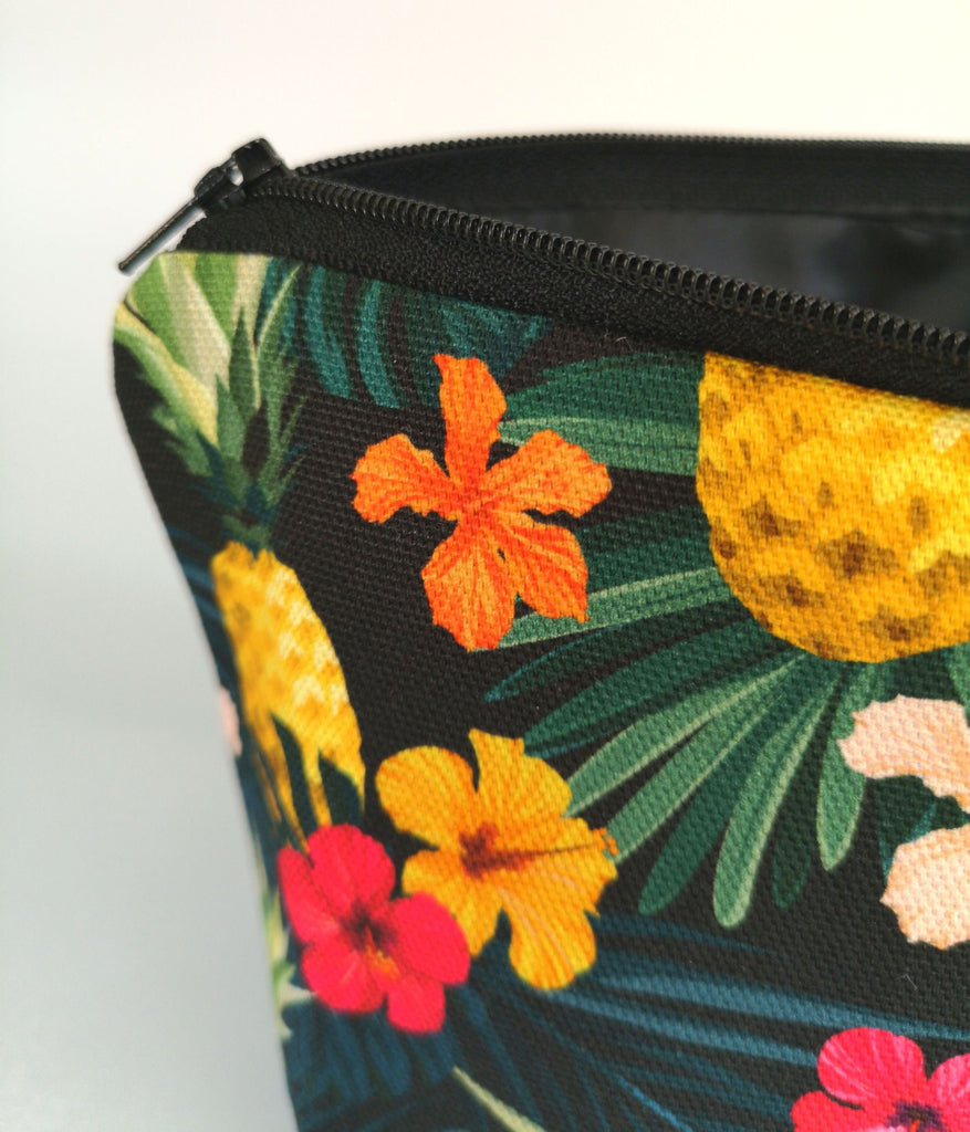 Tropical Makeup Bag featuring tropical pineapple floral print, with a black zip, close up, with the zip open to reveal a black water-resistant polyester lining, on a white background.