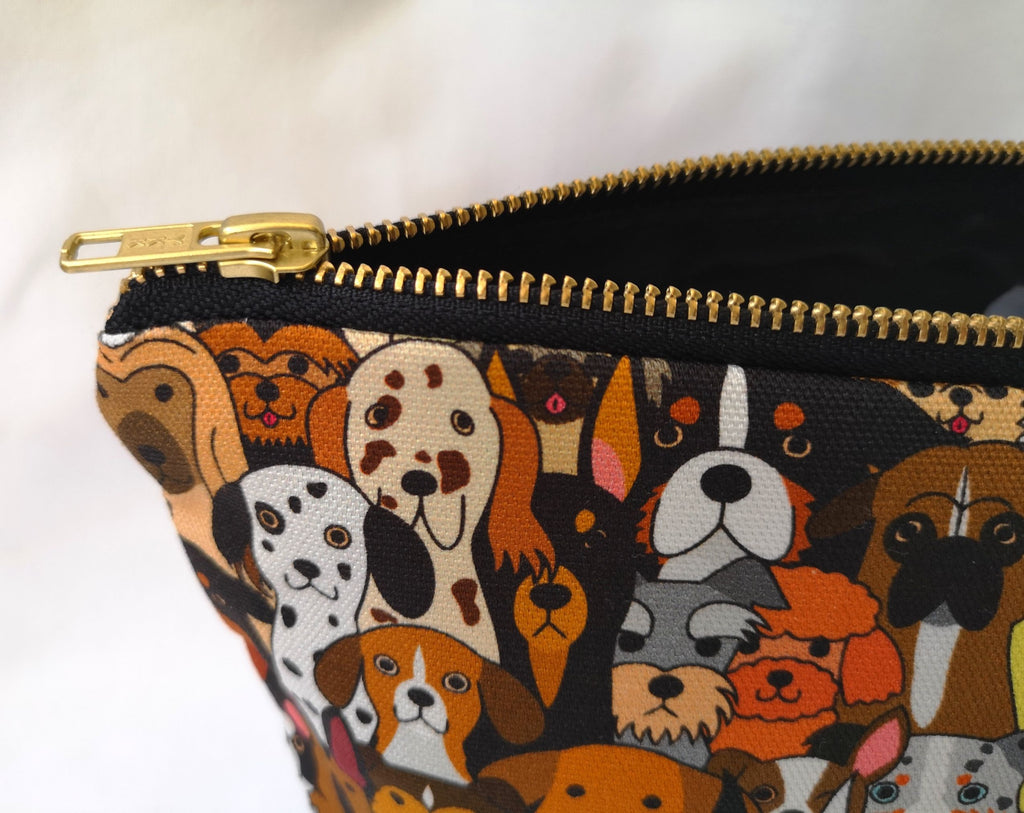 Large Toiletry Wash Bag for Women with stylish Dog print fabric, (the print features lots of different types of dog faces), with a quality brass YKK zip, close up, with the zip open to reveal a black water-resistant polyester lining, on a white background.