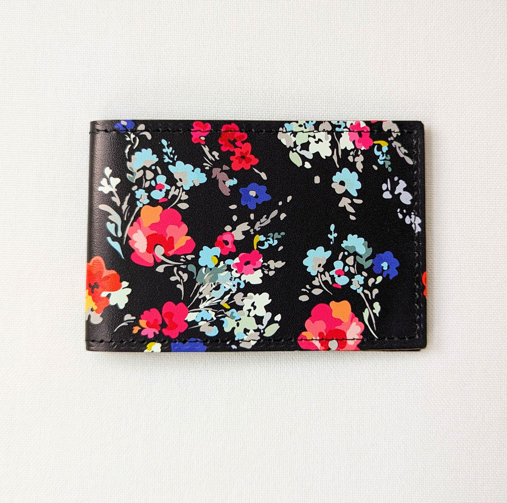 Recycled leather travel card holder, featuring a floral pattern on dark blue, placed on a white background 