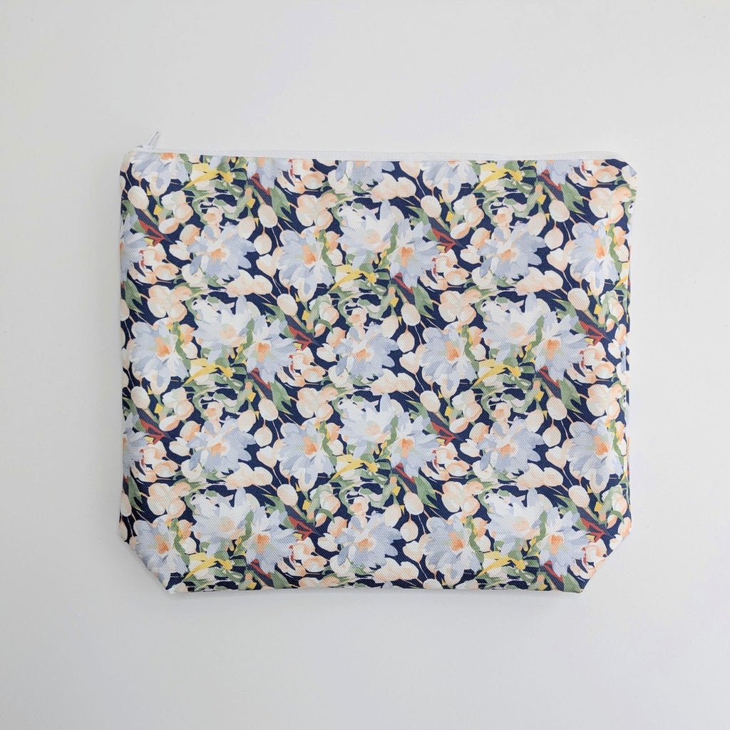 Large Cotton Wash Bag, featuring a stunning blossoming floral pattern design on a dark blue background, with polyester waterproof lining and a quality white nylon zip, on a white background, lying flat.