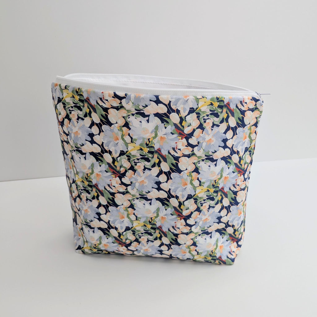 Large Cotton Wash Bag, featuring a stunning blossoming floral pattern design on a dark blue background, with polyester waterproof lining and a quality white nylon zip, on a white background, at a slight angle.