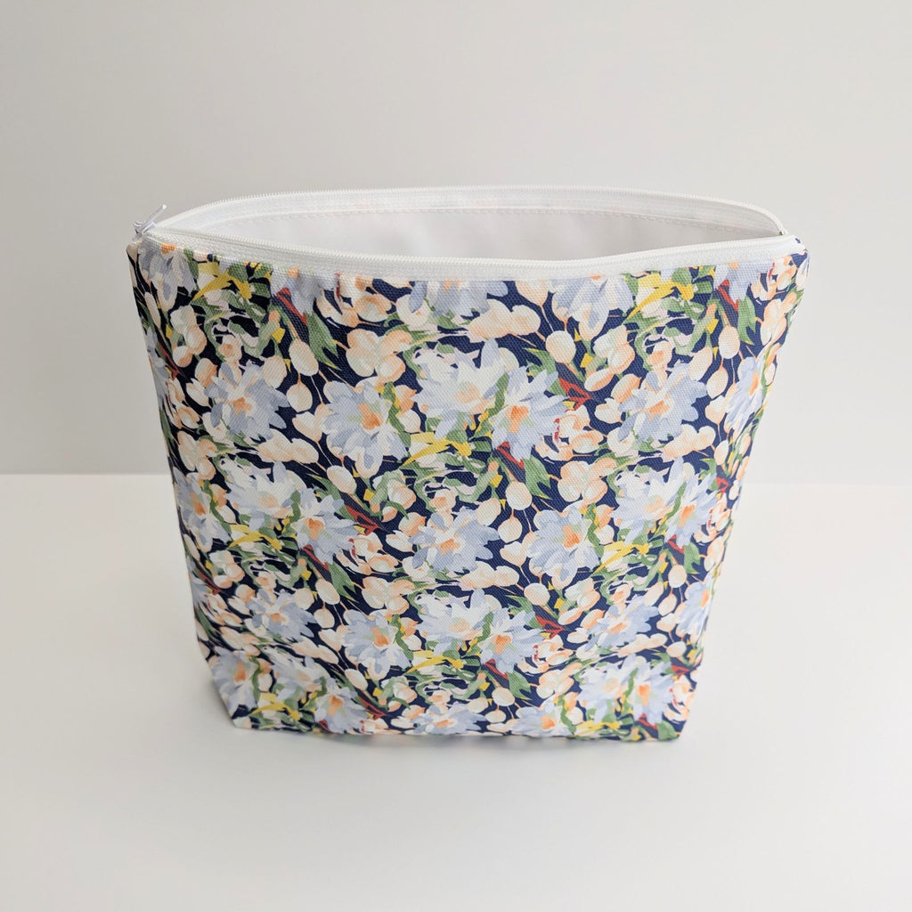 Large Cotton Wash Bag, featuring a stunning blossoming floral pattern design on a dark blue background, with polyester waterproof lining and a quality white nylon zip, on a white background, standing open and upright, showing some of the lining.