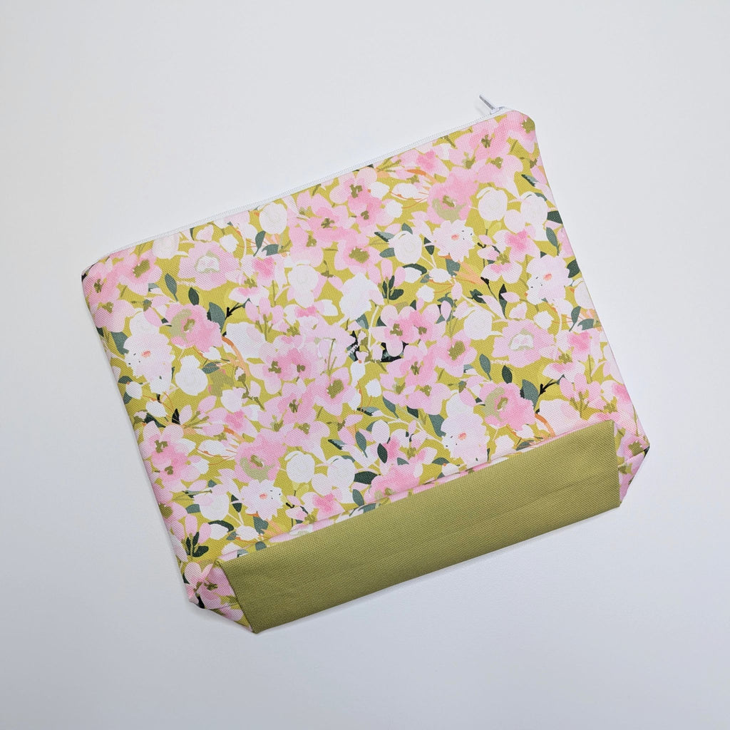 Large Wash Bag, adorned with a stunning cherry blossom floral design, featuring pink cherry blossom on a light green background, with a quality white nylon zip, lying flat, showing the gusseted bottom on a white background.