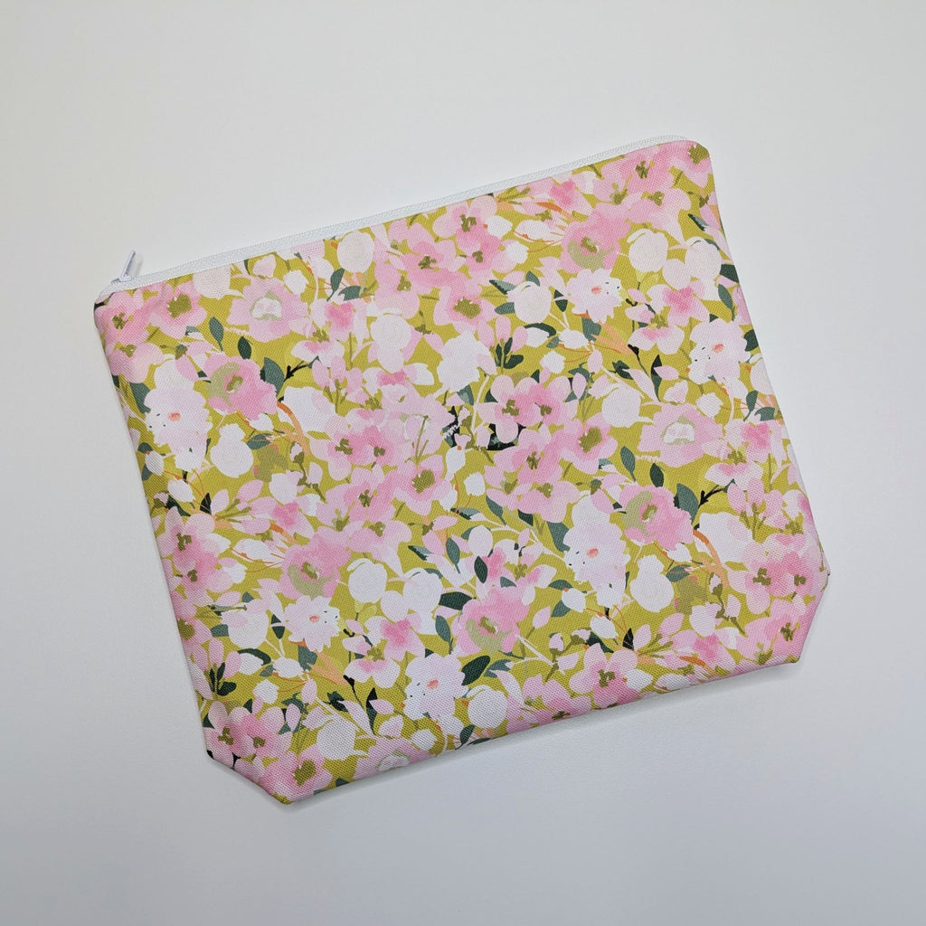 Large Wash Bag, adorned with a stunning cherry blossom floral design, featuring pink cherry blossom on a light green background, with waterproof lining and a quality white nylon zip, lying flat, at an angle, on a white background.