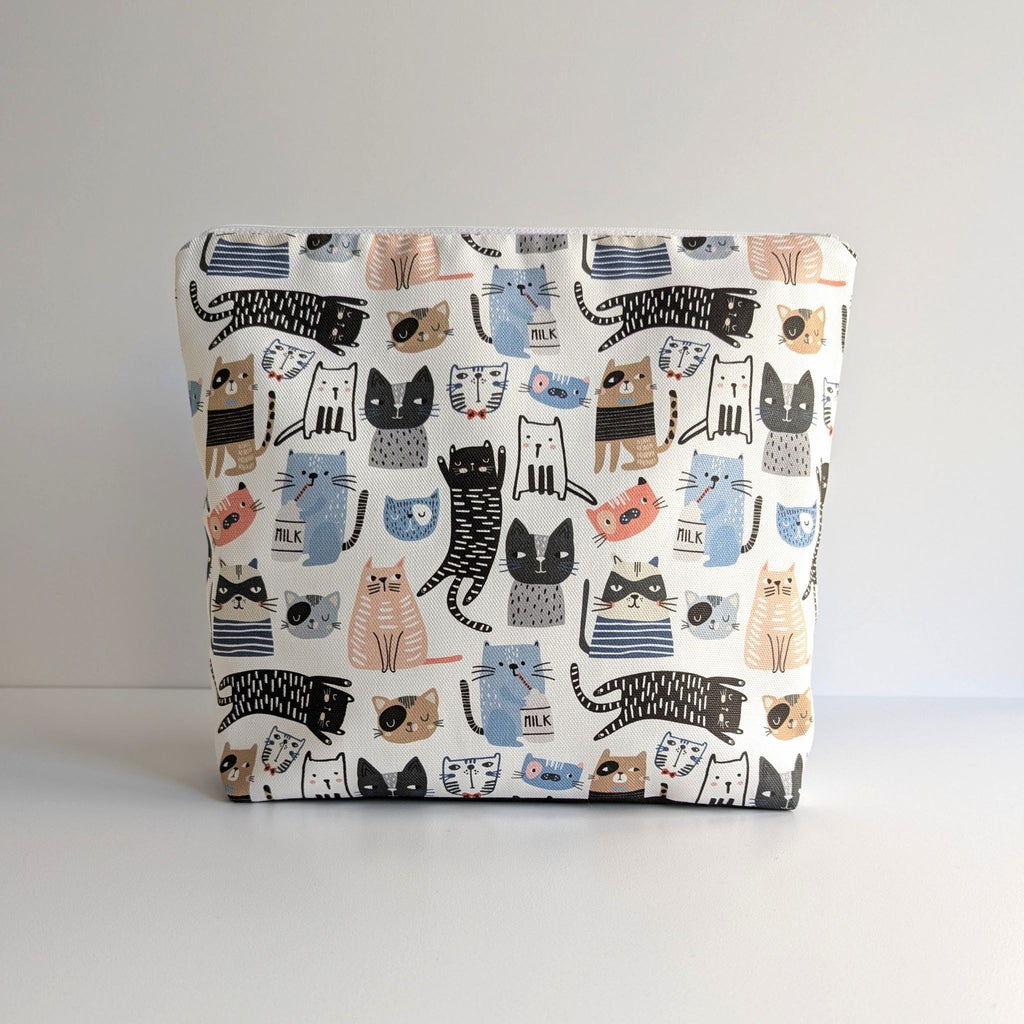 Large and generously sized cat print design wash bag with a 100% cotton outer, closed, fastening with a quality white nylon zip, and a gusseted boxed bottom, so that it sits upright, placed on a marble surface, with a white background.