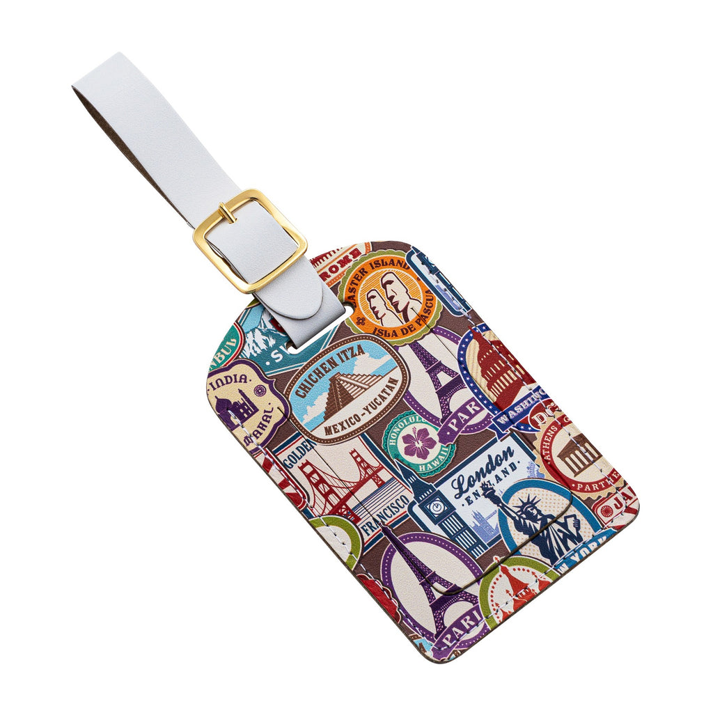 Recycled Leather Luggage Tag featuring travel themed print, with flap covering personal details card, with a white strap finished with a sleek gold-plated buckle to attach to luggage, at an angle, on a white background.