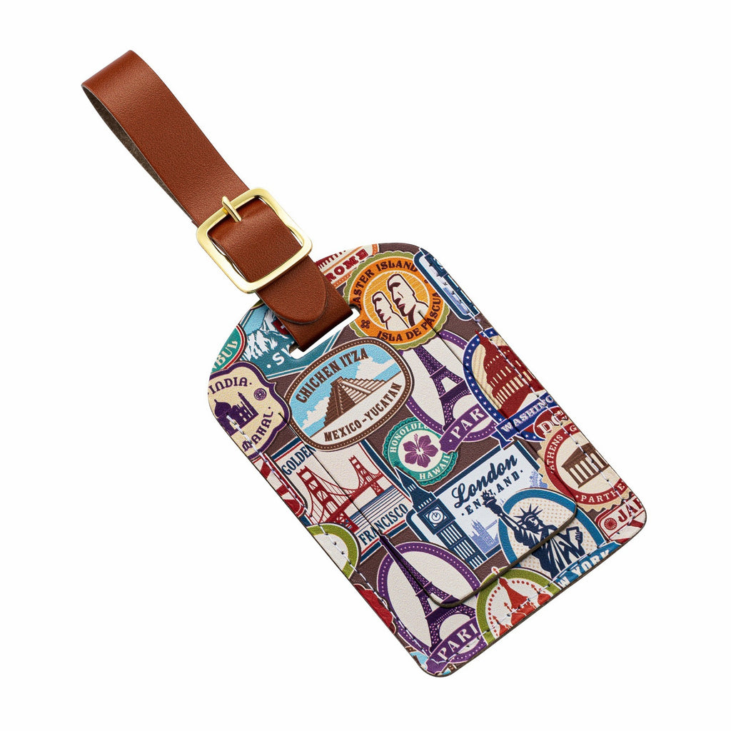Recycled Leather Luggage Tag featuring travel themed print pattern, with flap covering personal details card, with a brown strap finished with a sleek gold-plated buckle to attach to luggage, at an angle, on a white background.