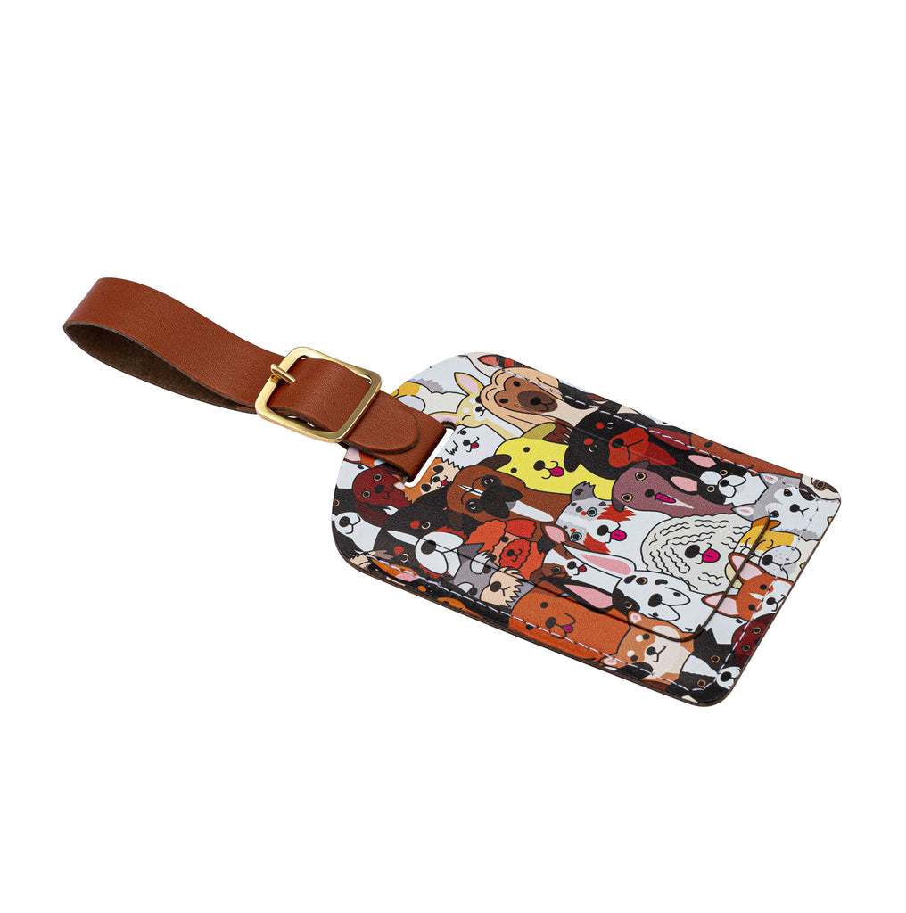 Side view of a Recycled Leather Luggage Tag featuring dog themed print pattern, with flap covering personal details card, with a brown strap finished with a sleek gold-plated buckle to attach to luggage, on a white background.
