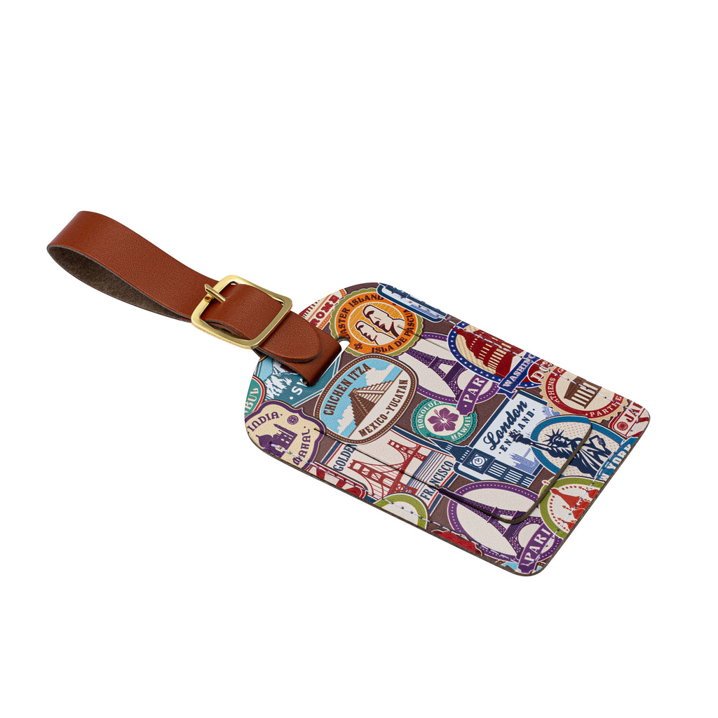 Side view of a recycled Leather Luggage Tag featuring travel themed print pattern, with flap covering personal details card, with a brown strap finished with a sleek gold-plated buckle to attach to luggage, on a white background.