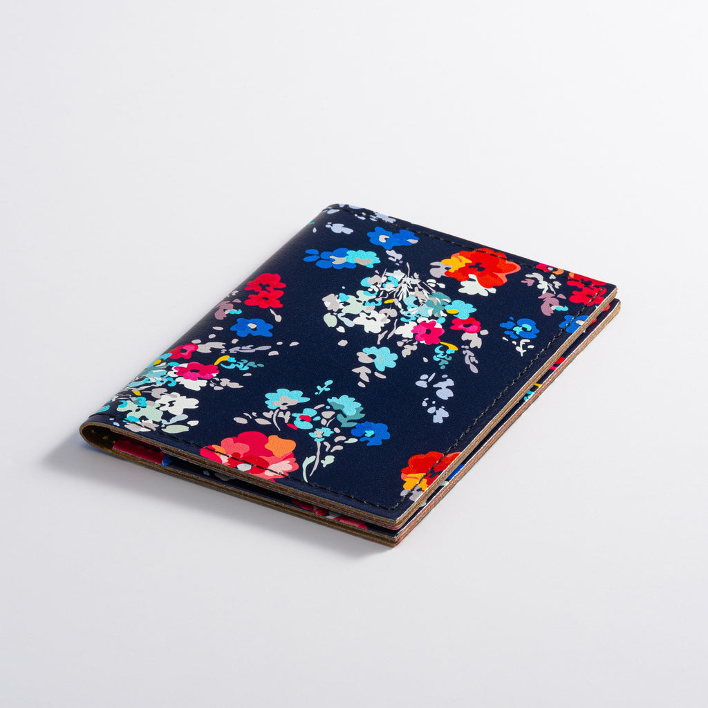 Recycled Leather Folding Wallet Card Holder for women, featuring a floral pattern on a dark navy-blue background, closed, on a white background.