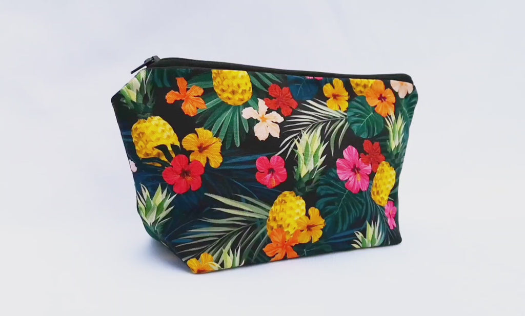 Tropical Makeup Bag featuring tropical pineapple floral print, with a black zip, sitting upright and closed, showing the side first and then the front, on a white background.